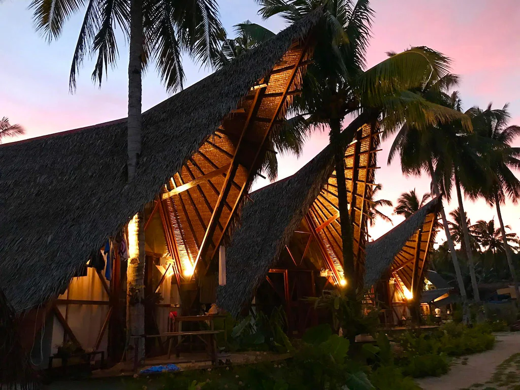 Tropical wooden villas at Dahun Villas Siargao powered by Cocotel surrounded by lush palm trees in Siargao Island, Philippines.