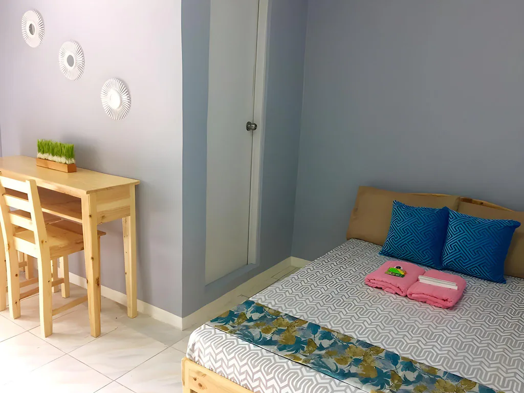 A tastefully decorated hotel room in a resort in Dasmarinas, Cavite, featuring a comfortable bed, a desk, a TV, and a window with a view of the outdoors.