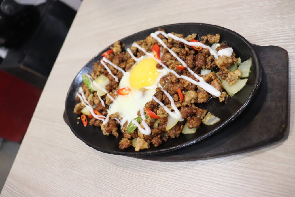 A sizzling hot plate of original Filipino pork sisig topped with red chili and calamansi at Aling Lucing's in Angeles City, Pampanga, the birthplace of sisig.