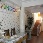 Reception area of Amigos Beach Resort in Boracay, Philippines, featuring a colorful rainbow sign, decorative bamboo chairs, a shell-patterned wall, and a staircase leading to upper rooms.