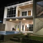Nighttime view of Arabella Hot Spring Resort in Laguna, featuring a private swimming pool and a modern two-story villa with warm lighting.