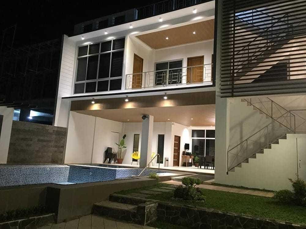 Nighttime view of Arabella Hot Spring Resort in Laguna, featuring a private swimming pool and a modern two-story villa with warm lighting.