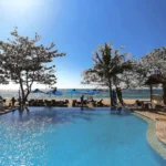 Luxury infinity pool overlooking the sandy beach and ocean sunset at Aureo Resort La Union in the Philippines.