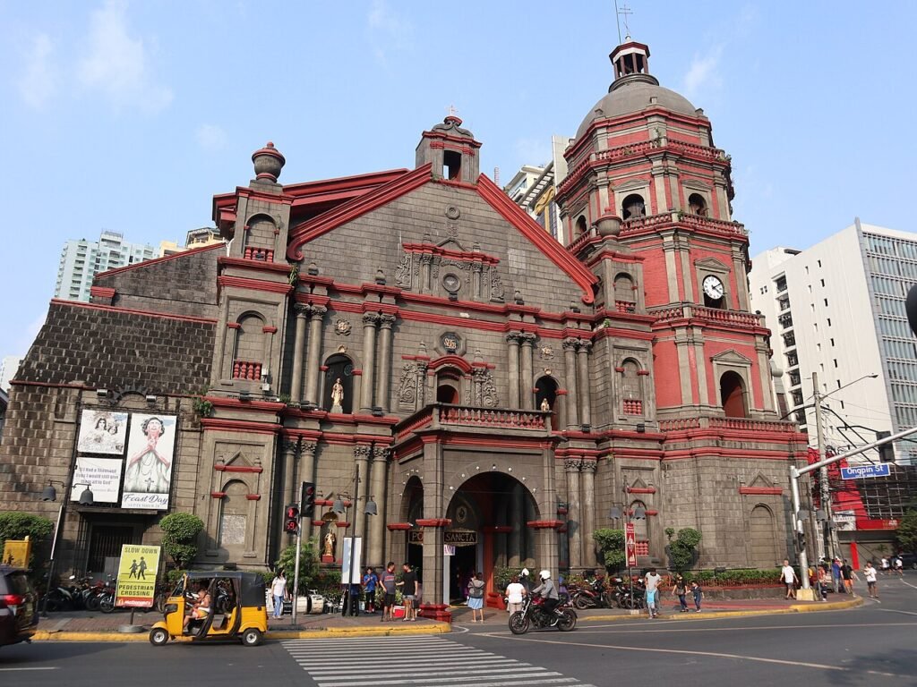 The historic dark stone facade of Binondo Church, also known as Minor Basilica of Saint Lorenzo Ruiz, fronting a vibrant Plaza San Lorenzo Ruiz in Binondo, Manila, Philippines.
