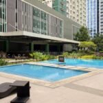 Modern studio apartment rental with balcony overlooking the swimming pool and cityscape in Cebu IT Park, Philippines.