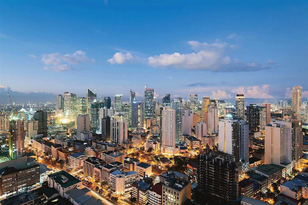 Panoramic city view of the Manila skyline at sunset from a window at The CityFlats Sacred Heart in the Philippines.