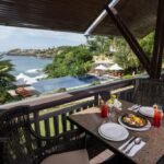 Al fresco balcony dining table set with Spanish paella at Club Punta Fuego in Nasugbu, Batangas, overlooking an infinity pool and the scenic ocean cove.