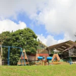 Outdoor children's playground featuring a blue swing set and tunnel crawling structures at Eden Nature Park and Resort in Davao City.