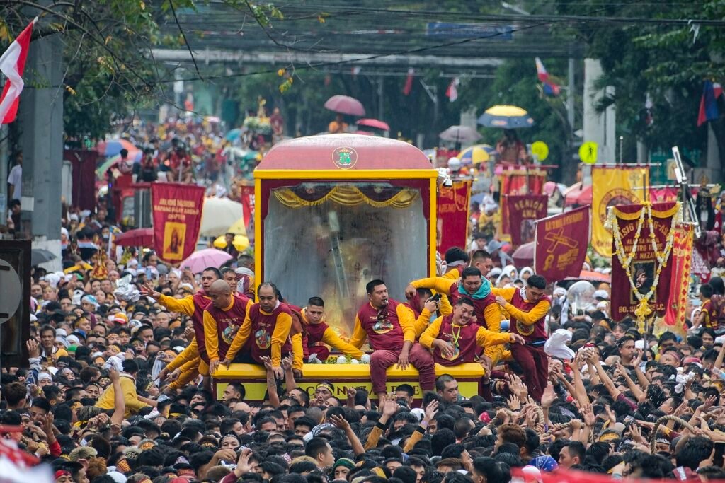 A massive crowd of passionate devotees wearing maroon and yellow celebrating the Feast of the Black Nazarene during the Traslacion procession in Manila, Philippines.