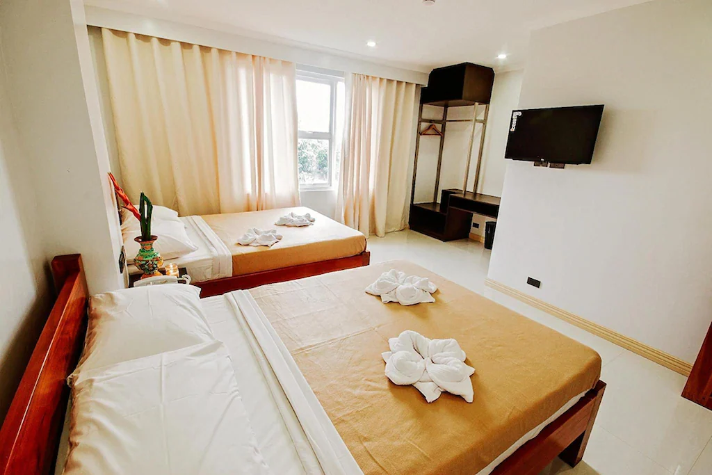 A beautifully designed, cozy hotel room at Hotel Lapira in Vigan, Ilocos Sur, featuring warm lighting, traditional wood accents, crisp white linens, and modern amenities.