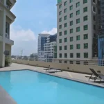 Rooftop swimming pool area at Mandarin Plaza Hotel in Cebu, featuring black sun loungers on a tiled deck overlooking surrounding city high-rises.