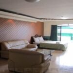 Spacious executive suite room at Natalia Hotel in Angeles, Clark, Philippines, featuring a leather sofa seating area, a large bed, a wooden accent wall, and a private balcony.
