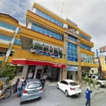 Street-level view of Obdulia's Business Inn in Dumaguete City, a multi-story yellow building featuring an LBC outlet and a 7-Eleven store at the ground level.