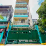 Low-angle exterior view of OYO 840 Orangenest Apartelle in Manila, showing a multi-story cream building behind a tall green metal gate.