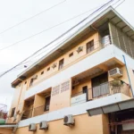 Low-angle view of the yellow and white multi-story exterior facade of RedDoorz near Baclay Drive Super Metro in Cebu, showing private balconies and aircon units.