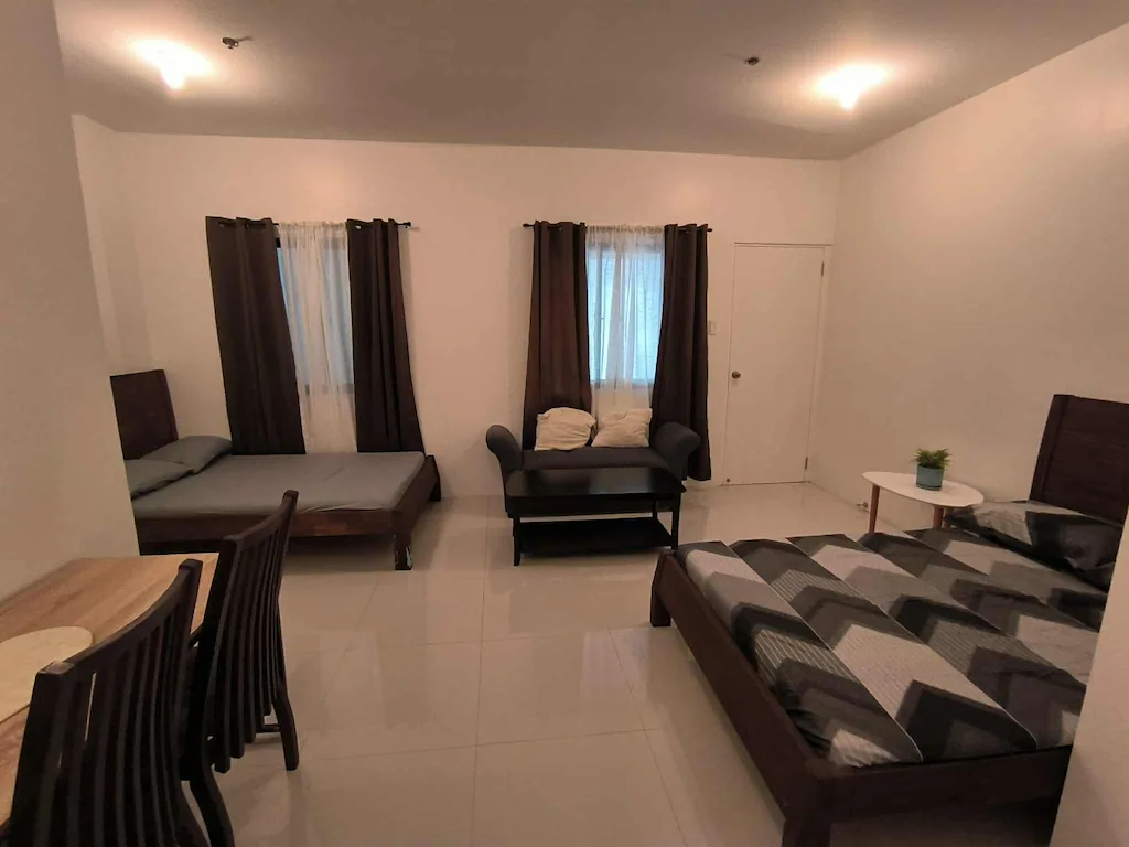 Bright and modern studio room interior at Yujia Apartment in Manila, Philippines, featuring a comfortable bed, large windows with city views, and sleek contemporary decor.