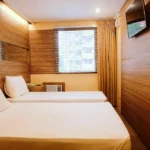 Cozy and modern boutique room interior at Spaces Hotel Makati in Manila, Philippines, featuring contemporary decor, warm lighting, and a large window with a city view.