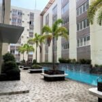 An outdoor lap swimming pool and courtyard area lined with palm trees between multi-story residential buildings at Stanford Suites 3 in Cavite.