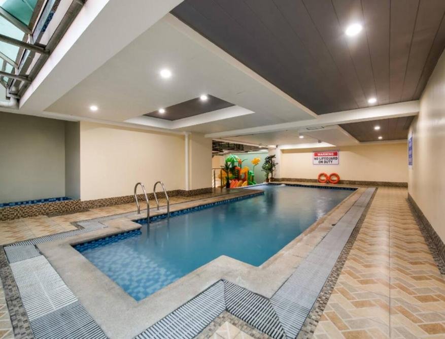 Outdoor rooftop swimming pool at Bay Area Suites Manila in the Philippines, featuring clear blue water and a scenic city view.
