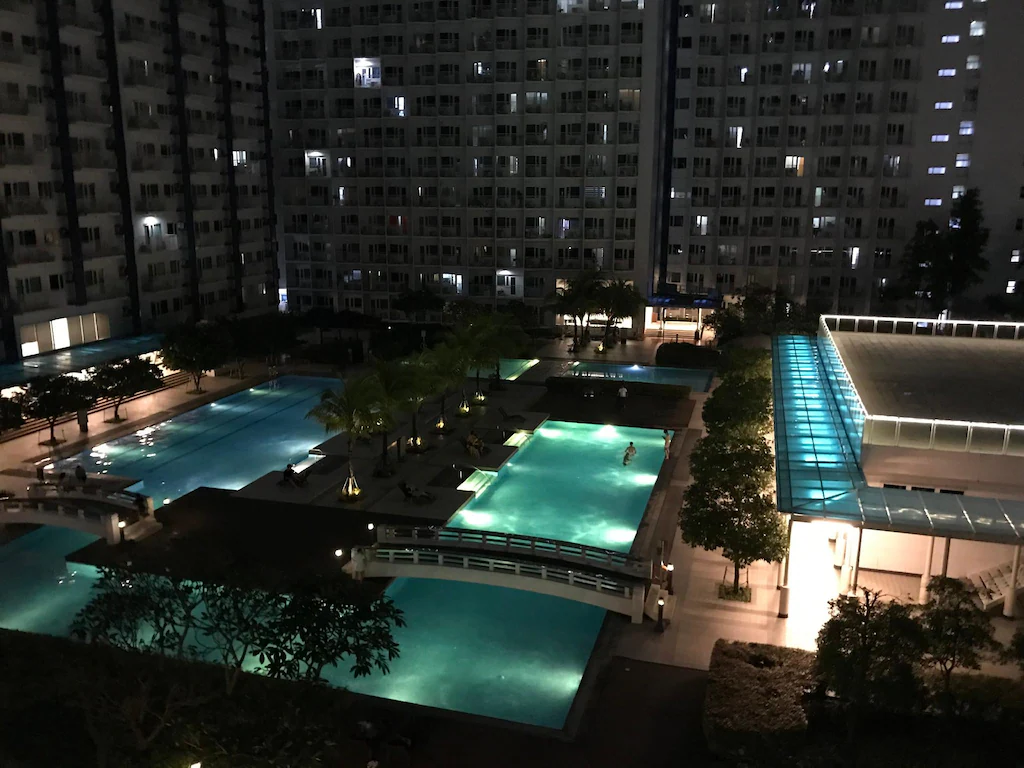 Vibrant resort-style swimming pool view from a private condo patio at SM Jazz Residences in Makati, Manila, Philippines.