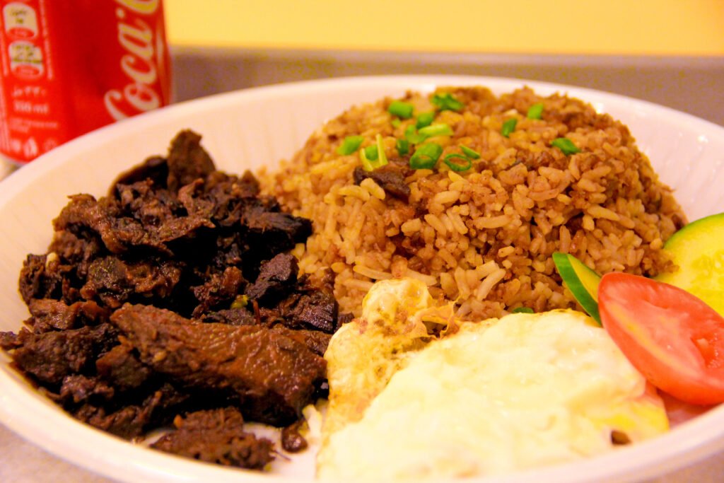 A traditional Filipino Tapsilog breakfast featuring cured beef strips, garlic fried rice, and a fried egg served on a plate at Artemis Place Makati Hotel in Manila, Philippines.