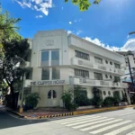 Three-story white Art Deco building of The Clipper Hotel in Manila, featuring curved balconies, round porthole windows, and a corner entrance.