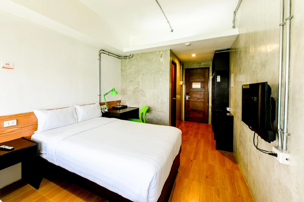 Cozy and affordable air-conditioned room interior at Travelbee Seaside Inn in Bohol, Philippines, featuring clean beds, wooden furnishings, and a welcoming ambiance for travelers.