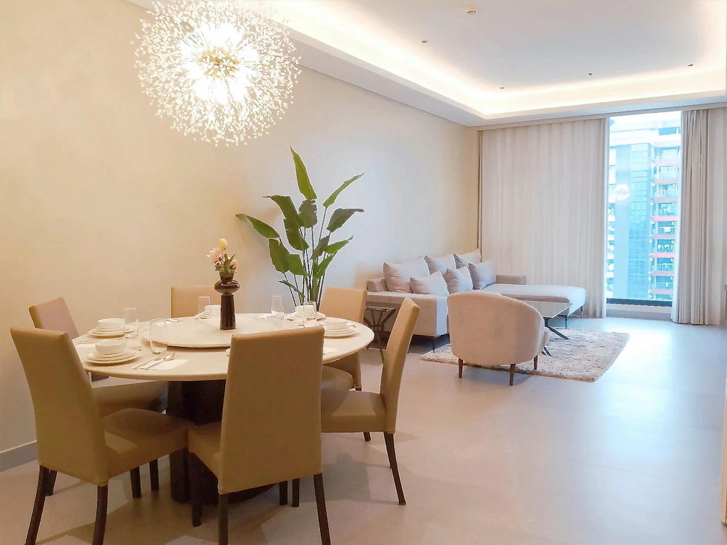 View of the spacious Family Junior Suite at Bayprime Hotel, highlighting the elegant dining area with a round table for six and the open-plan living room.