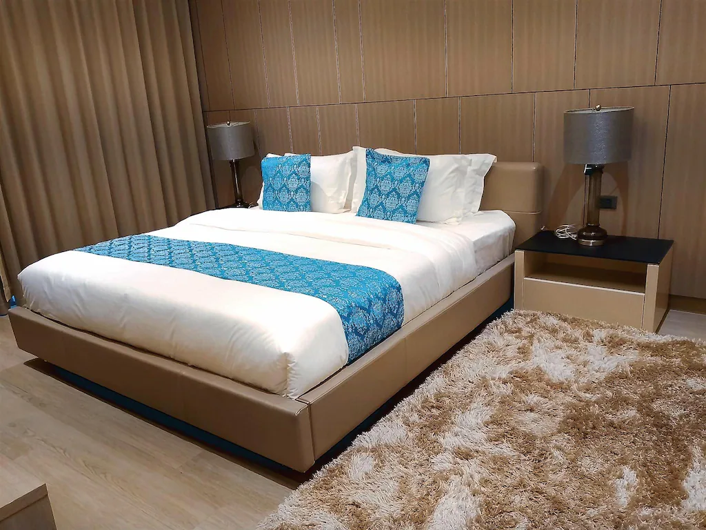 Modern living room area of the Family Junior Suite at Bayprime Hotel, featuring a large beige L-shaped sectional sofa, a flat-screen TV, and a plush area rug.