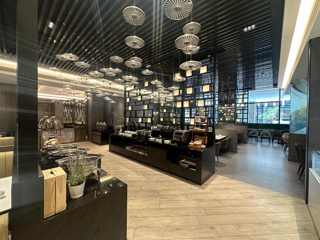 Modern buffet and restaurant dining area inside Bayprime Hotel Manila, featuring elegant dark wood partitions, hot food stations, and decorative hanging lights.